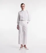 Camisa blanca de crepé con cuello solapa, abotonada, mangas largas abullonadas y sin estampado.