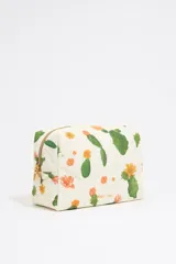 Neceser grande de nylon color crudo con estampado de flores y cactus, cierre con cremallera dorada y logo metálico de la marca.