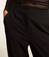 Pantalón de vestir blanco, de corte recto, con bolsillos laterales y traseros. Se ajusta a la cintura con cierre tradicional.