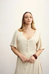 Vestido midi color beige con textura, escote en V, mangas cortas y abotonadura frontal.