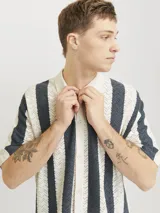 Polo de hombre con tejido texturizado a rayas verticales color crema y gris, corte holgado, cuello tipo polo, mangas cortas y cierre con botones.