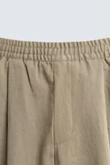 Pantalón negro de corte relajado con cintura elástica ajustable y pliegues en la parte delantera. Presenta bolsillos laterales y bolsillos traseros de parche.