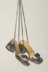 Sandalias plateadas de cuero con tacón bloque y tiras finas para atar al tobillo.