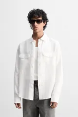 Sobrecamisa verde militar de lino, corte relaxed fit, con cuello solapa, manga larga con puños abotonados, bolsillos de parche con solapa en el pecho, aberturas laterales en el bajo y cierre frontal abotonado.