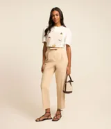 Remera blanca de corte slim con cuello redondo y mangas cortas abullonadas. Presenta un estampado frontal con diseño de picnic en tonos beige, con detalles bordados de abeja, cesta, hongo y texto en francés.
