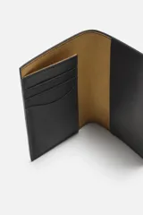 Cartera negra para pasaporte fabricada en piel, con tres posiciones para tarjetas y dos ranuras laterales.