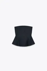 Top negro con escote recto y hombros descubiertos. Tiene hilo metalizado y bajo peplum. Cierre lateral con cremallera oculta.