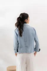 Blazer celeste de denim 100% algodón, entallado y corto a la cadera, con cuello y solapa amplios, mini bolsillos delanteros y bordado con el logo de la marca en el interior del puño.