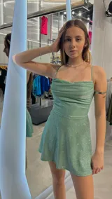 Vestido corto verde brillante con breteles finos, escote drapeado y falda evasé.