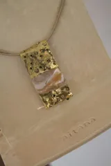 Collar con dije rectangular de bronce con perforaciones y pieza central de nácar.