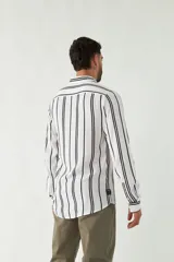 Camisa de mangas largas con estampado a rayas verticales en tonos verde oliva, blanco y azul. Corte regular y logo bordado en el pecho. Confeccionada en viscosa.