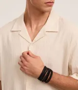 Kit de seis pulseras negras de estilo casual, compuesto por tres pulseras trenzadas con ajuste deslizante y tres pulseras de cuentas elásticas, algunas con detalles cilíndricos.