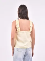 Blusa sin mangas color amarillo pálido, con breteles anchos con volados y escote cuadrado.