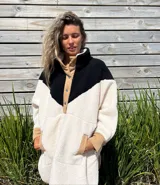 Buzo tipo poncho de polar color crudo con bloque superior en negro y detalles en beige.