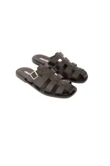 Sandalia plana negra de cuero vacuno con tiras entrelazadas y hebilla lateral metálica.