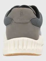 Zapatillas grises de tejido de punto con cordones, suela blanca y detalles en marrón.
