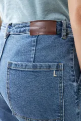 Pantalón jean culotte de tiro alto, color azul medio, con bolsillos delanteros y traseros, y botones metálicos.