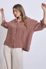 Camisa de lino color terracota, con cuello camisero, botones frontales y mangas amplias de tres cuartos.