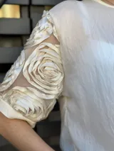 Blusa color crema de mangas cortas con detalle de rosas en relieve en las mangas.