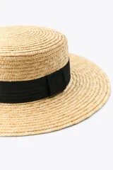 Sombrero de paja natural con ala ancha y cinta negra contrastante alrededor de la base de la copa.
