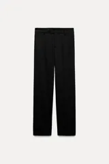 Pantalón negro de tiro bajo con trabillas en la cintura. Cuenta con bolsillos laterales y de vivo en la espalda, detalle de raya planchada en el delantero y cierre frontal con cremallera, botón y gancho metálico.