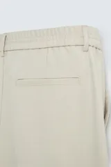 Pantalón de vestir color beige, corte wide fit, con cintura elástica, pliegues frontales, bolsillos laterales y traseros de vivo.