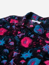 Campera de poliéster con cuello camisero, cierre frontal con botones y estampado floral en tonos rosa y celeste sobre fondo negro.