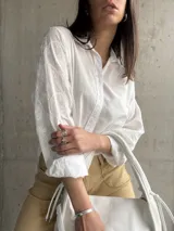 Camisa blanca de manga larga con bordado floral en las mangas.