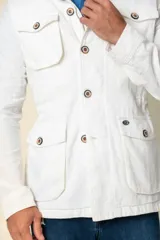 Cazadora blanca de lino con cuello camisero, cierre con botones, cuatro bolsillos frontales con solapa y corte entallado.