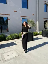 Vestido negro de corte midi, con mangas largas ajustadas y cuello redondo. Incluye cinturón ancho con apliques circulares.