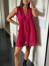 Vestido corto blanco de algodón con bordado tipo broderie anglaise, escote en V y mangas cortas con volado. Presenta un corte imperio con frunce bajo el busto.