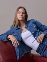 Campera de jean azul de la marca Baccini, con cuello solapa, abertura central con botones metálicos, bolsillos delanteros y ruedo desflecado.