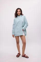 Camisa oversize a rayas verticales color amarillo y blanco, con cuello camisero, manga larga y cierre frontal con botones.