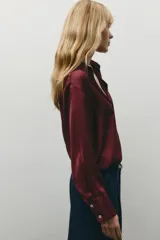 Camisa color borgoña de satén con cuello solapa, escote en pico, manga larga y cierre frontal con botones.