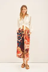 Pantalón capri con estampado floral en tonos naranja, rojo, azul y marrón. Tiene corte regular, bolsillos laterales y elástico en la parte trasera de la cintura.