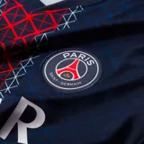 Camiseta de fútbol Nike del Paris Saint-Germain, modelo Stadium, temporada 2025/26, para hombre. Diseño azul con franja vertical central con patrón de cruces rojas y blancas. Incluye logo de Nike, escudo del club y sponsor Qatar Airways en el frente.