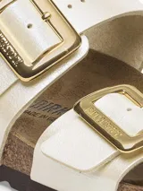 Sandalias Birkenstock modelo Sydney, color blanco con hebillas doradas.
