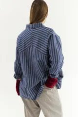 Camisa de algodón con mangas raglán y estampado a rayas, presenta botones en el frente y bolsillos.