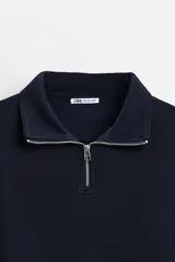 Sudadera negra de cuello alto con cierre frontal de cremallera, corte relaxed fit, manga larga y terminaciones en rib.