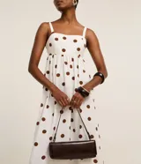 Vestido midi evasé sin mangas, confeccionado en tejido airflow color blanco con estampado de lunares marrones. Presenta escote corazón, breteles anchos con elásticos y lastex en la espalda.