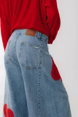 Pantalón de jean azul de corte ancho con apliques de crochet blancos en forma de corazón, diamante, trébol y pica.