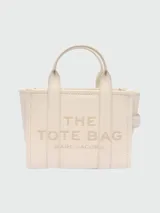 Bolso tote pequeño de cuero texturizado color gris con doble asa corta superior y correa larga extraíble y ajustable para llevar al hombro. Estampado frontal con el texto "The Tote Bag" y el nombre de la marca.
