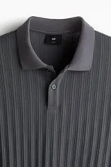 Remera polo gris de punto texturizado de peso medio, corte slim fit, manga corta, cuello clásico, tapeta de botones y bajo recto.