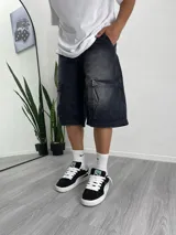 Bermuda de jean negro con efecto lavado, corte holgado y bolsillos cargo laterales.