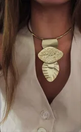 Gargantilla dorada con tres dijes colgantes de bronce con diferentes texturas.