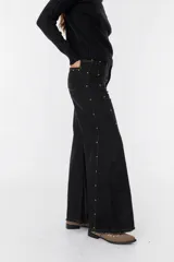 Pantalón beige de corte amplio con detalles de encaje en los costados y cierre frontal.