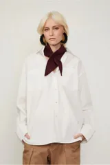 Camisa blanca amplia de algodón, con dos bolsillos en el frente, abotonada y con puños anchos.