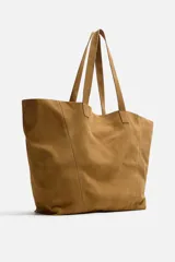 Bolso tipo shopper color marrón claro, fabricado en piel serraje. Cuenta con dos asas de mano y un bolsillo interior con cierre de cremallera.