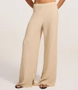 Pantalón largo color beige, de poliéster texturizado, con cintura elástica y bolsillos laterales.