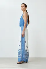 Pantalón blanco con estampado floral y guarda geométrica en tonos de azul.